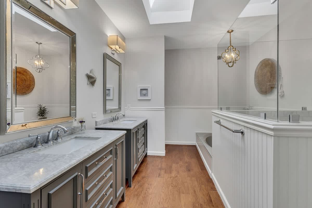 Pamper yourself in this luxurious master bathroom with dual vanities, marble countertops, and elegant pendant lighting creating your perfect retreat.