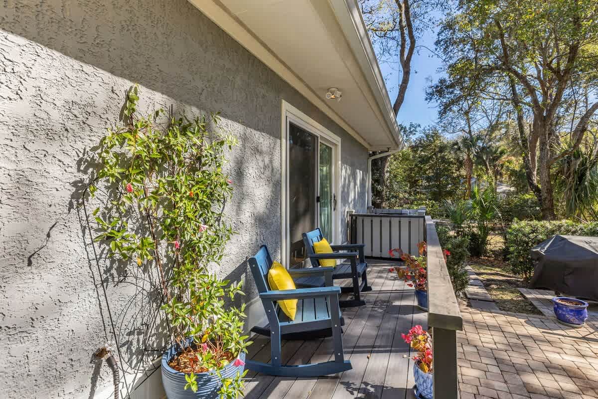 Your private deck awaits with colorful outdoor chairs and lush garden views, perfect for morning coffee or evening relaxation.