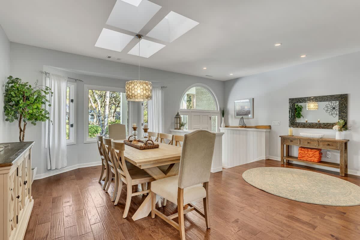 Gather around this inviting dining table where natural light pours through the skylight, creating the perfect setting for memorable meals together.