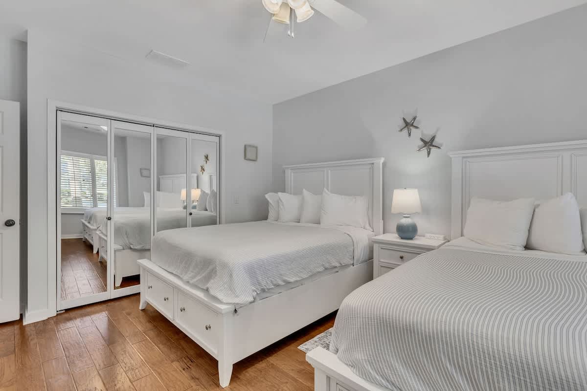 Drift off to peaceful sleep in this serene bedroom featuring two comfortable beds with crisp linens and warm lighting.