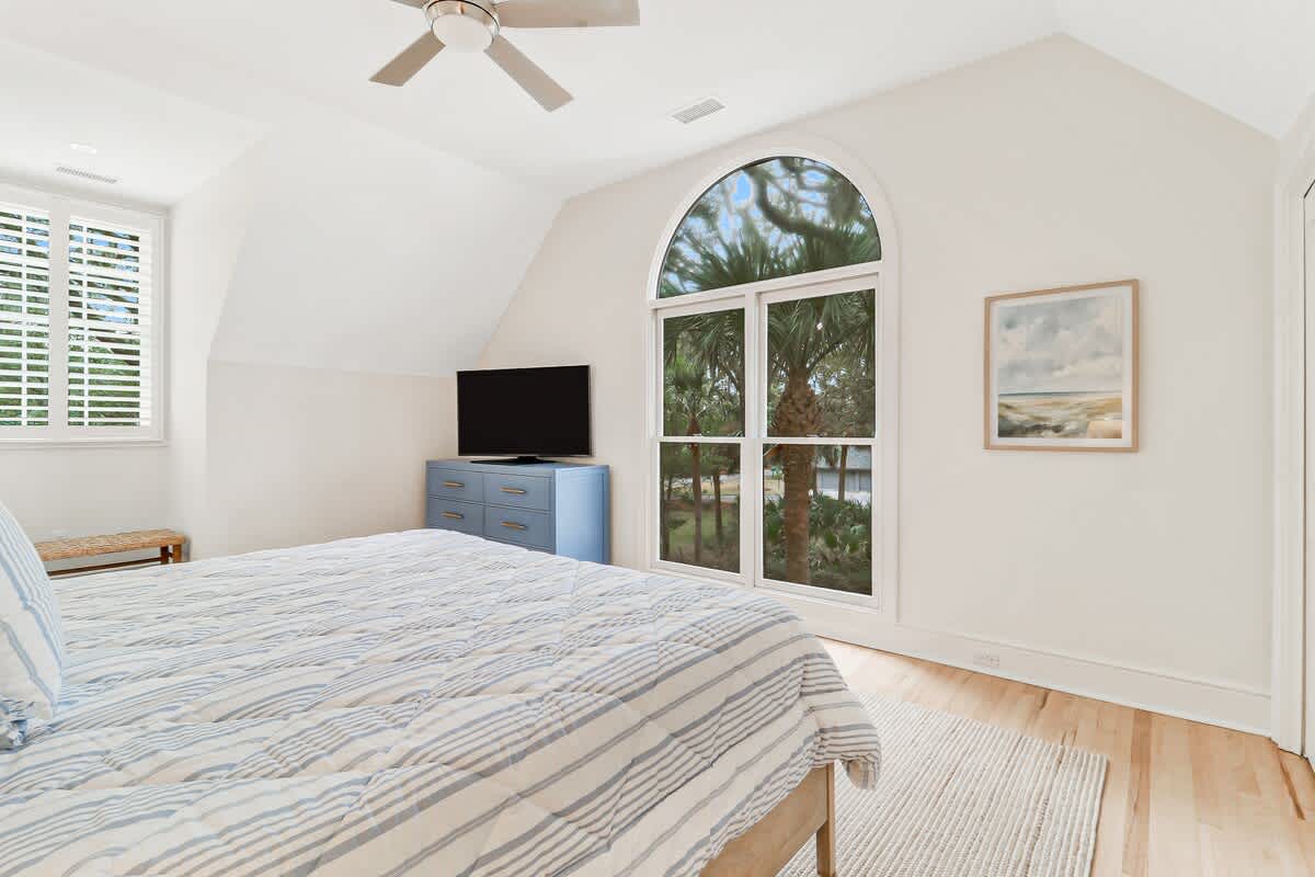 Wake up in your peaceful coastal retreat with palm tree views and gentle sea breezes through the arched window.