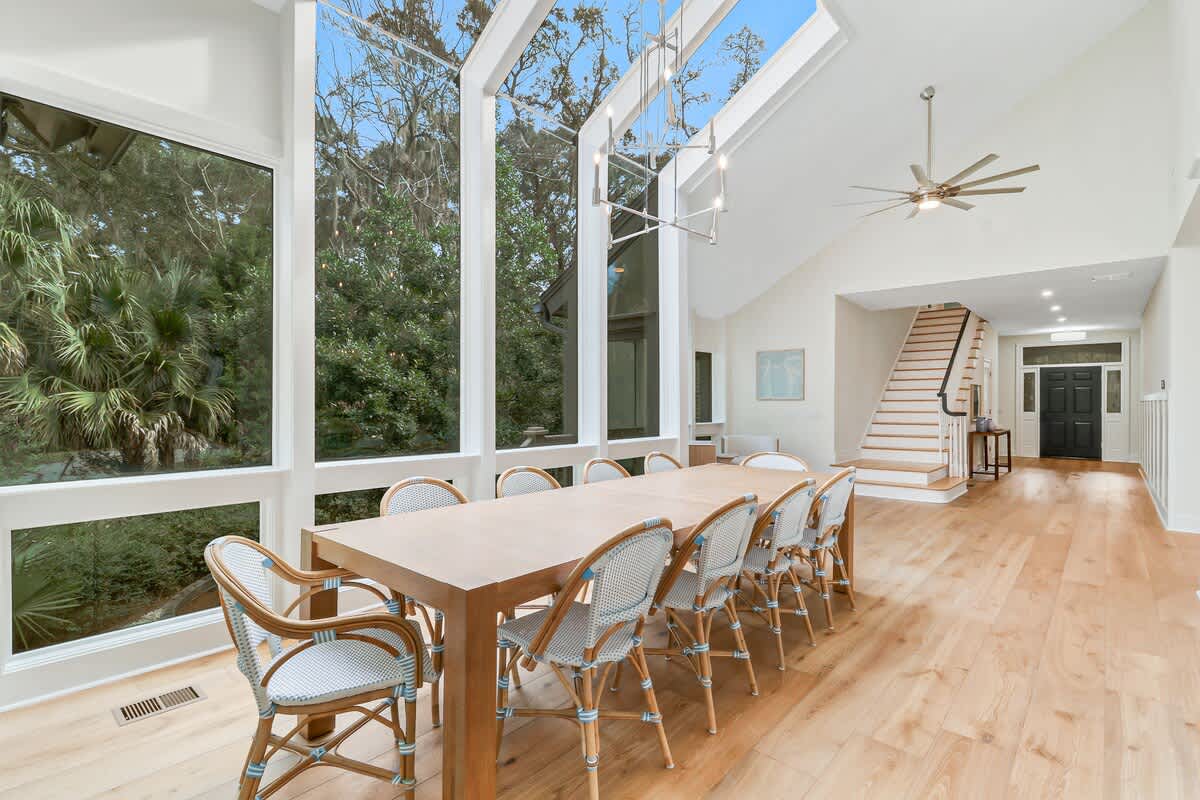Gather around this elegant dining table where floor-to-ceiling windows frame lush garden views, creating your perfect space for memorable meals together.