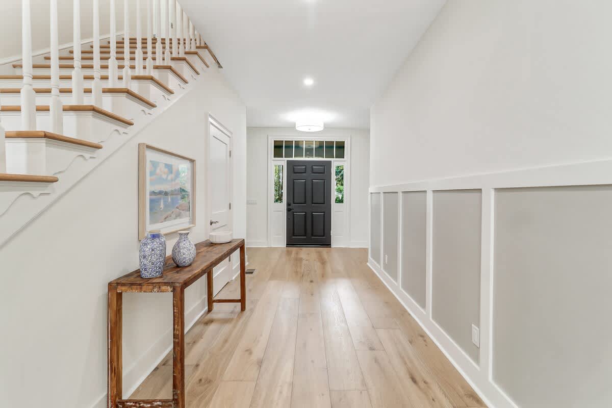 Step into your bright, welcoming entryway where warm wood floors meet elegant white walls, creating the perfect first impression for your stay.