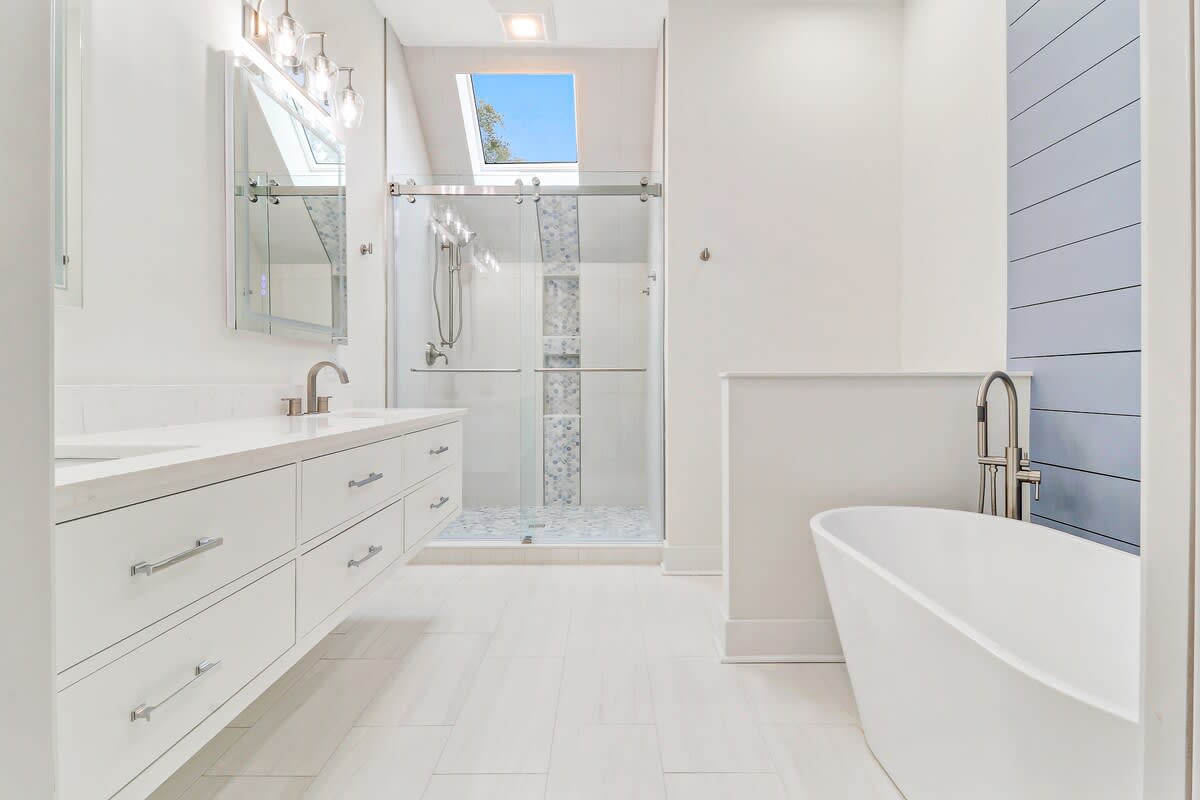 Indulge in luxury with your private spa-like bathroom featuring a soaking tub, glass shower, and abundant natural light streaming through the skylight.