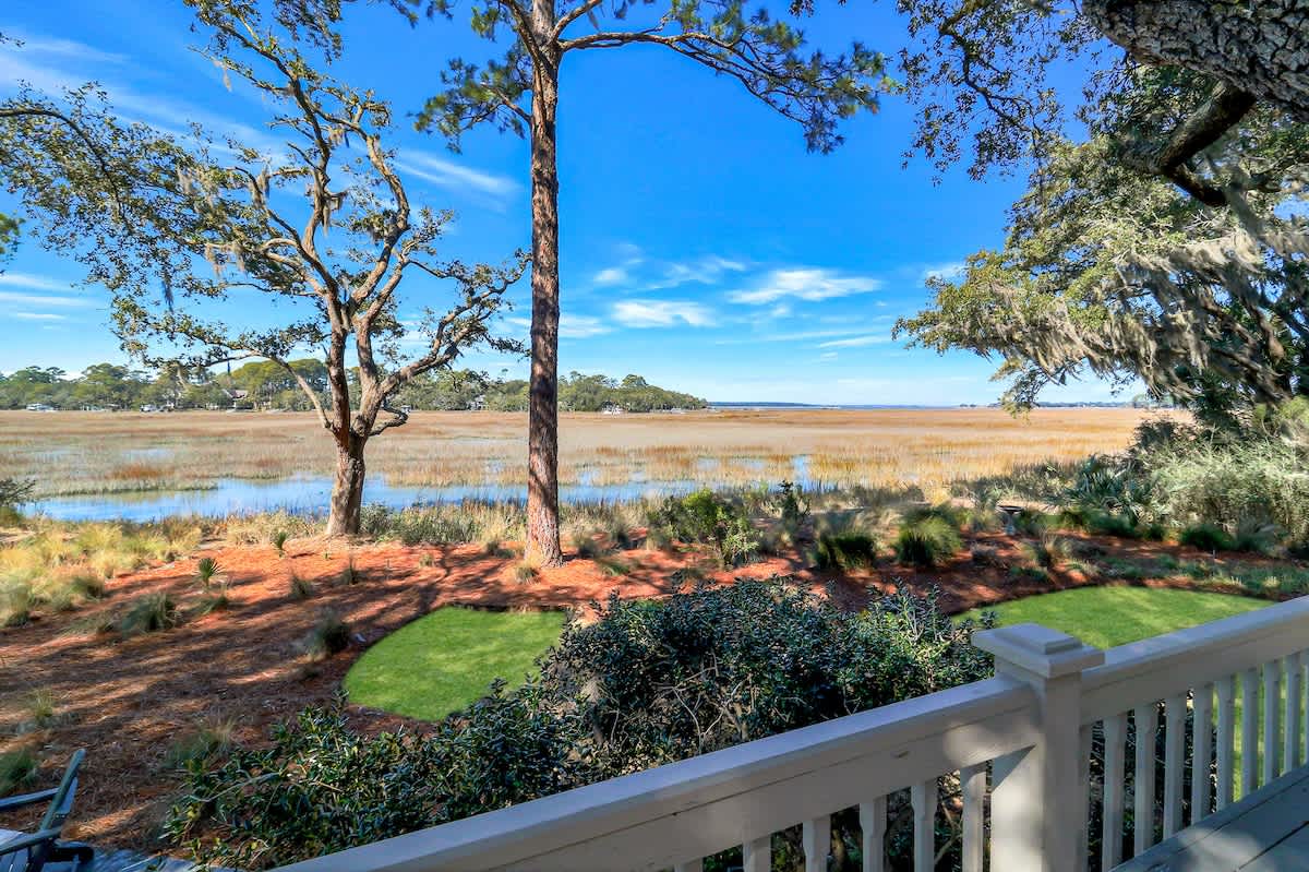 Expansive marsh views stretch toward the horizon from this elevated vantage point, framed by native trees and landscaped grounds below.