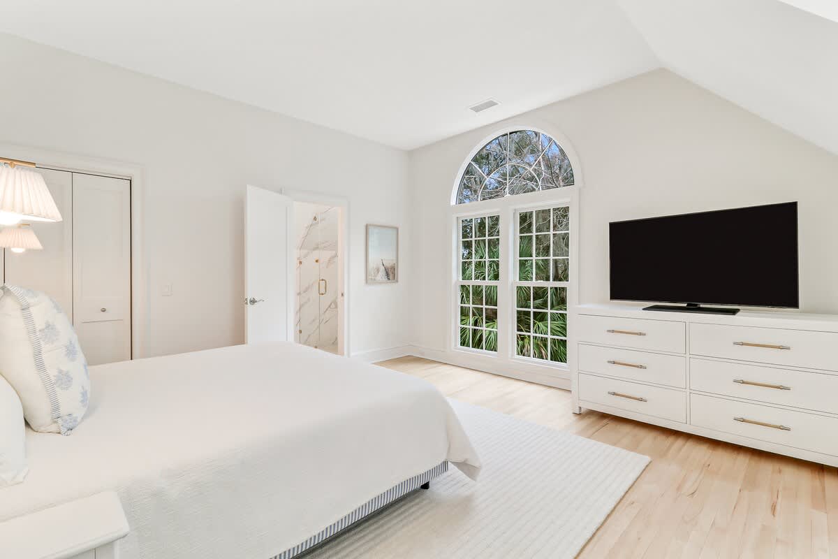 Unwind in your serene bedroom sanctuary with crisp linens and natural light streaming through elegant arched windows.