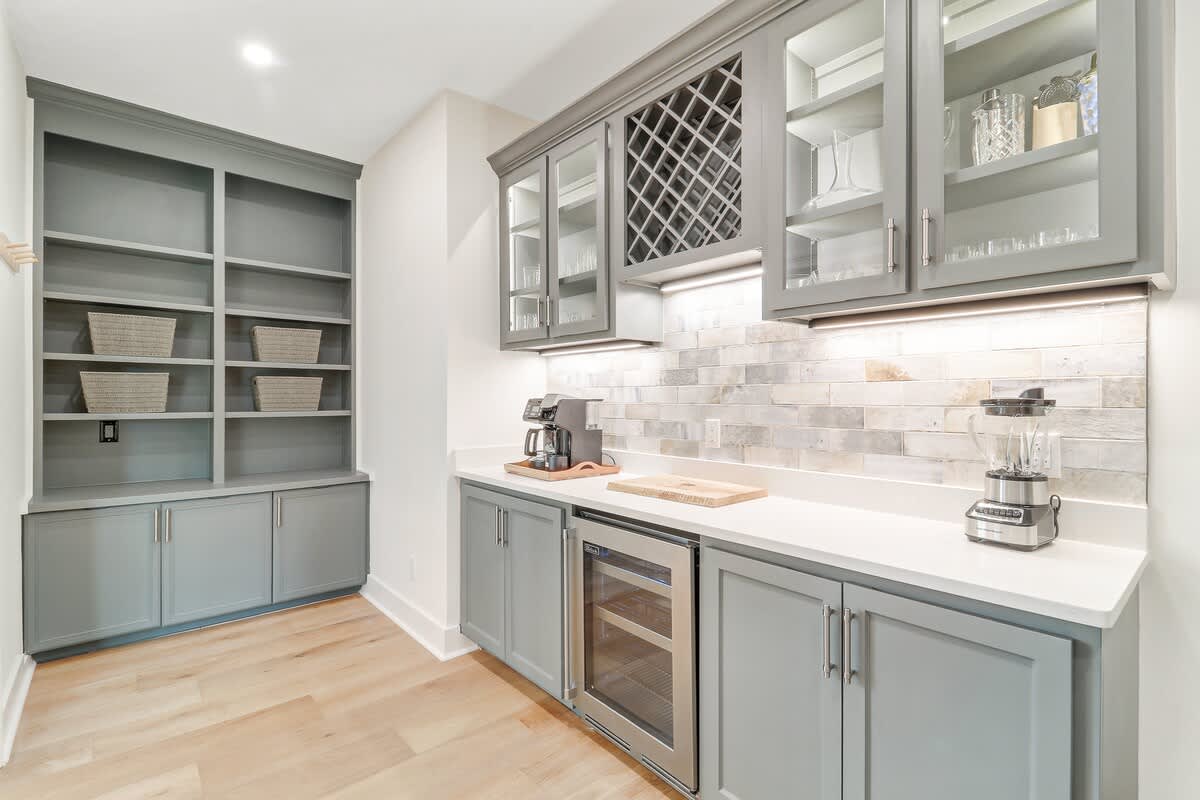Your elegant butler's pantry features sage green cabinetry, wine storage, and marble countertops perfect for entertaining prep.