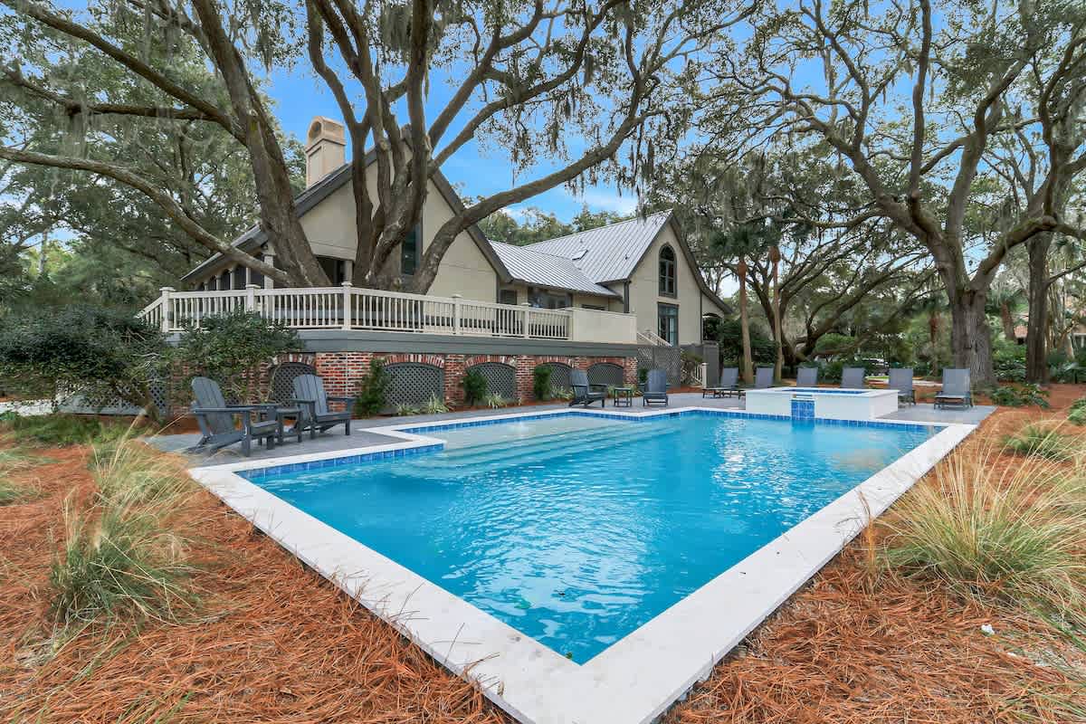 Jump into your private pool paradise, surrounded by majestic oak trees and elegant outdoor seating areas perfect for relaxation.