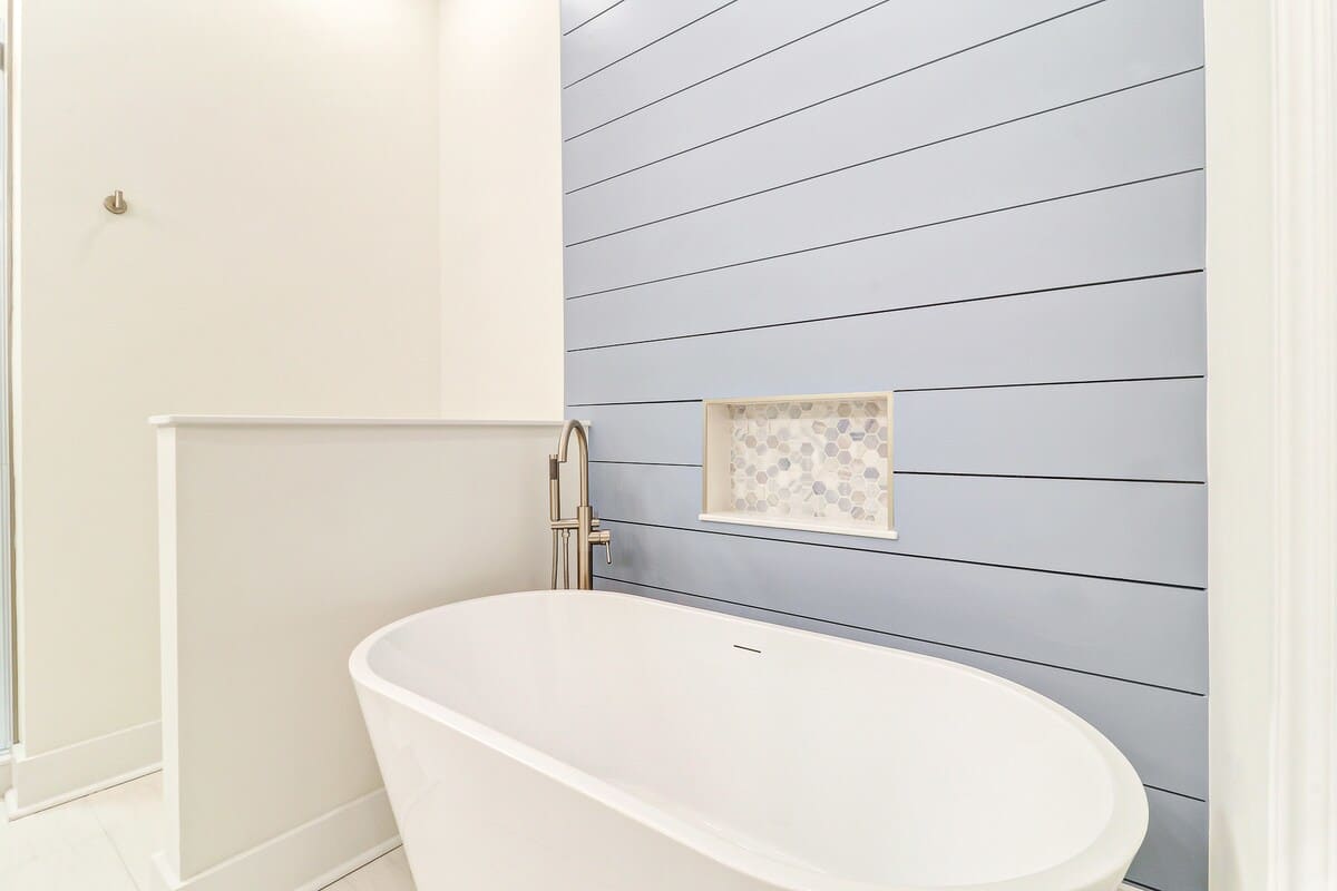 Sink into pure relaxation in your elegant soaking tub, where modern design meets coastal charm with shiplap walls and honeycomb tile details.