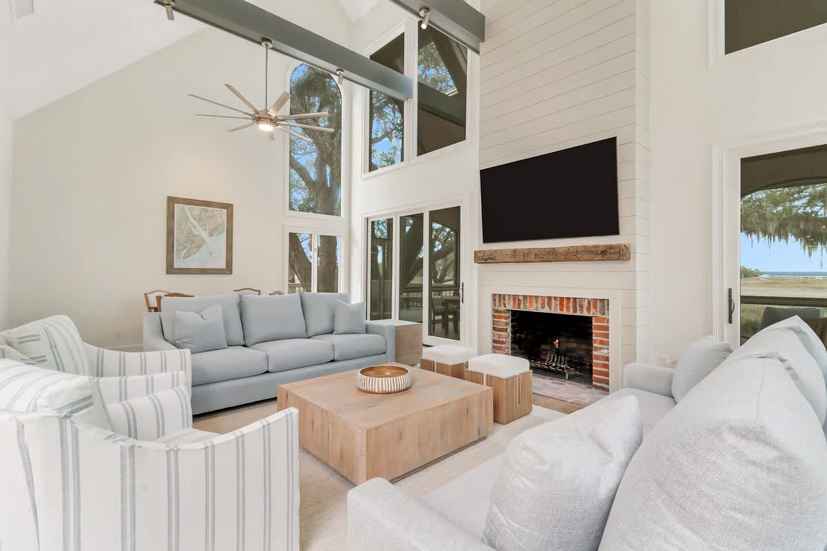 Relax in this stunning living room with soaring ceilings, where natural light pours through expansive windows while you enjoy the cozy fireplace.