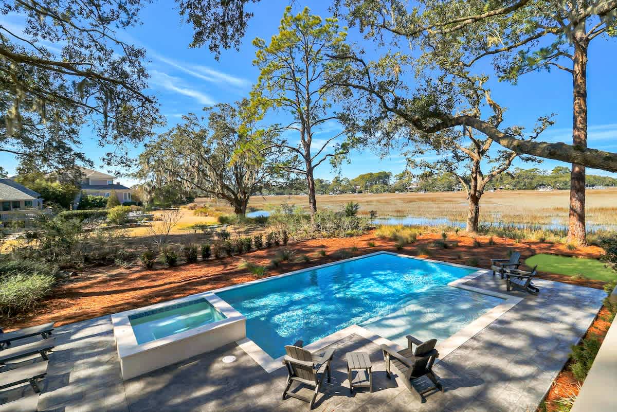Sparkling pool and spa with stunning marsh views create your perfect retreat under ancient oaks.