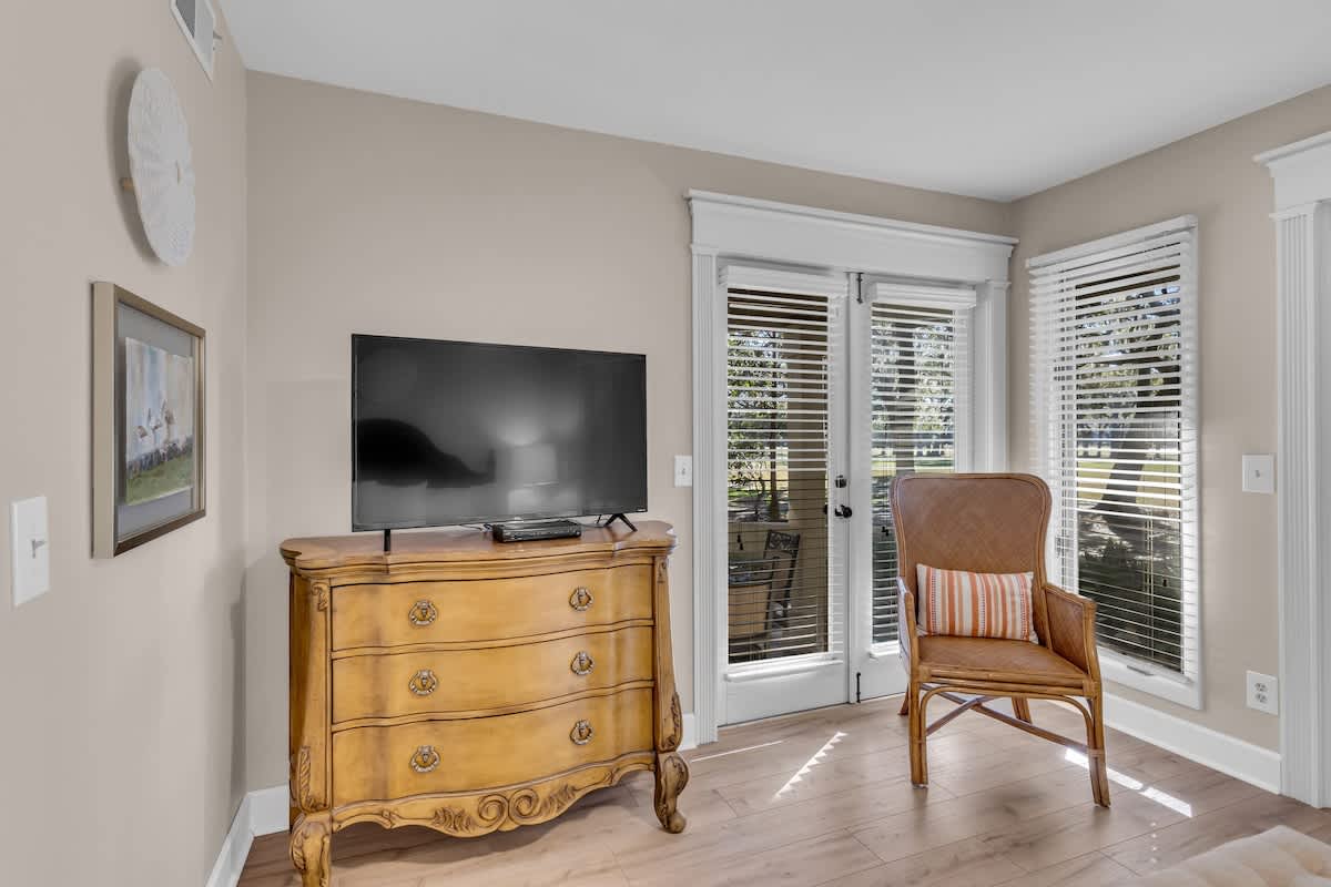 Unwind in your bright corner retreat with classic furnishings, modern TV, and peaceful garden views through elegant French doors.
