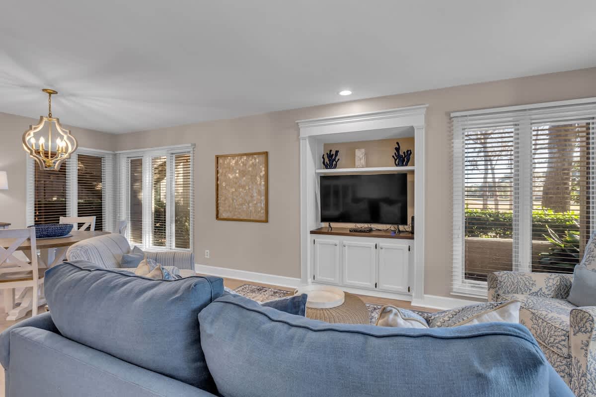 Sink into plush blue sofas and unwind in your elegant living space, complete with built-in entertainment center and charming coastal décor.