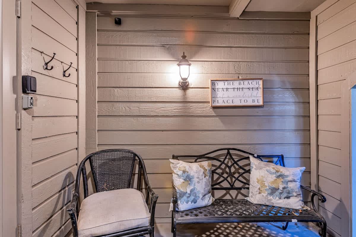Unwind on your private covered patio with cozy seating, coastal charm, and soft evening lighting creating the perfect retreat.