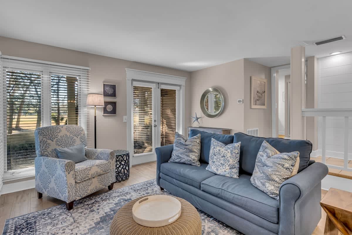 Sink into this cozy blue sofa surrounded by coastal charm, where natural light streams through your private patio doors.
