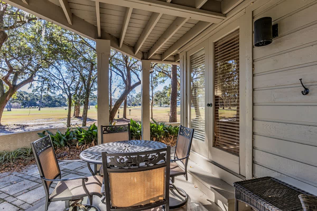 Enjoy morning coffee on your private covered patio, where comfortable seating and peaceful park views create the perfect outdoor retreat.