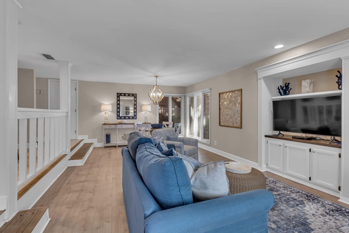 Sink into plush blue sofas in your elegant living space, where warm lighting and built-in entertainment center create the perfect gathering spot.