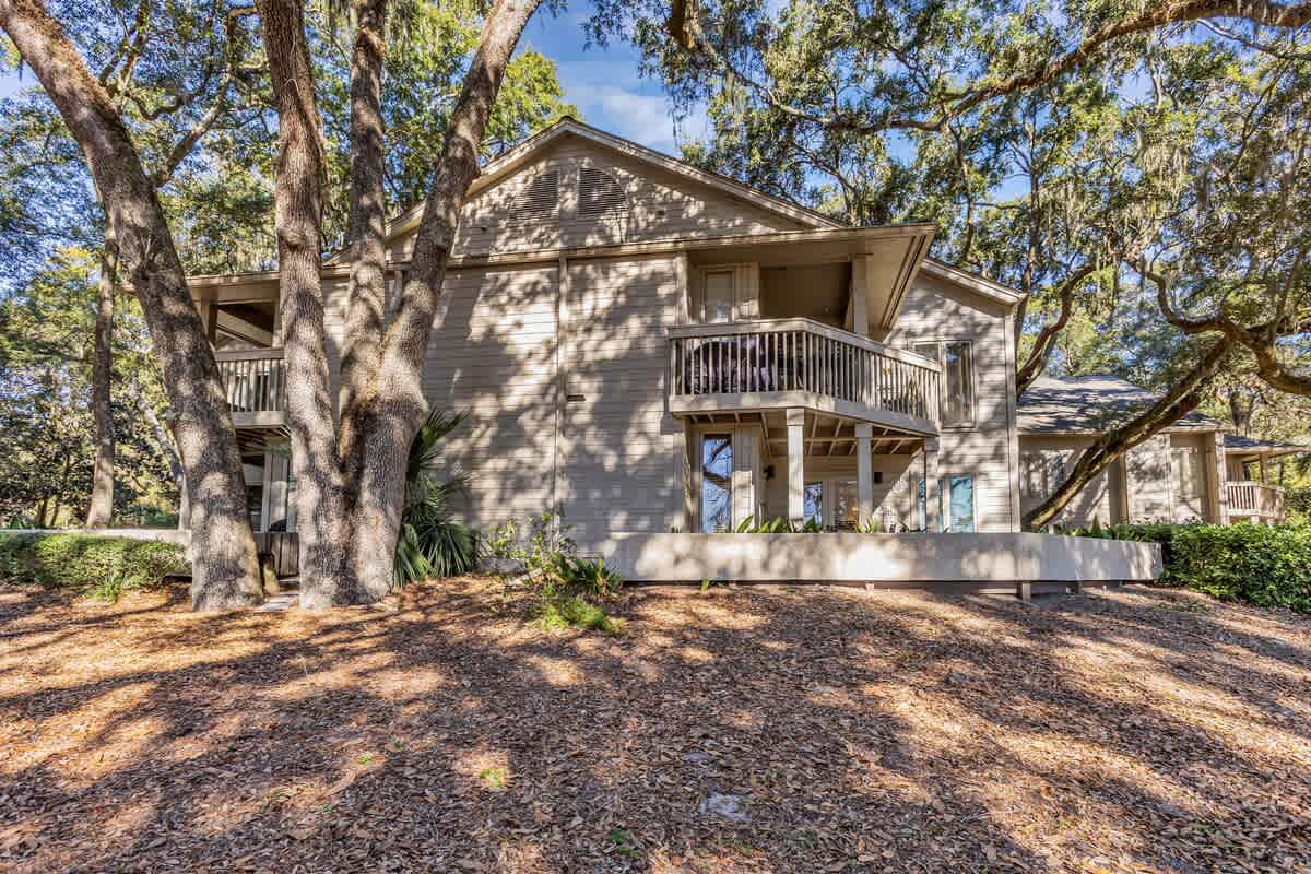 A charming two-story coastal home nestled among mature oak trees, offering peaceful surroundings and natural shade for your getaway.
