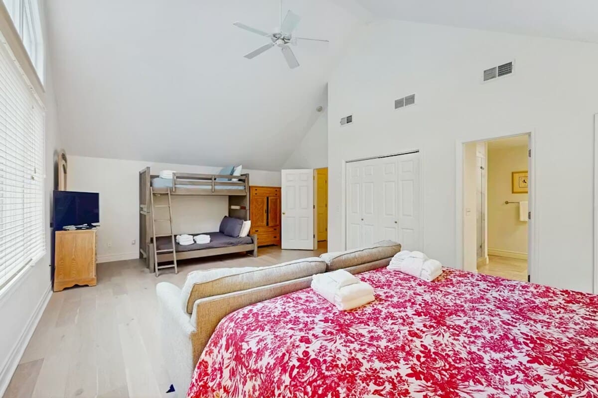 Rest comfortably in your spacious bedroom featuring a queen bed with soft linens, bunk beds for extra guests, and refreshing ceiling fan.