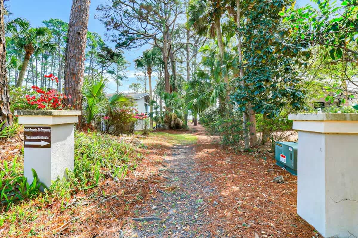 Property entrance with tropical landscaping and mature trees creates a welcoming arrival experience in this lush neighborhood setting.