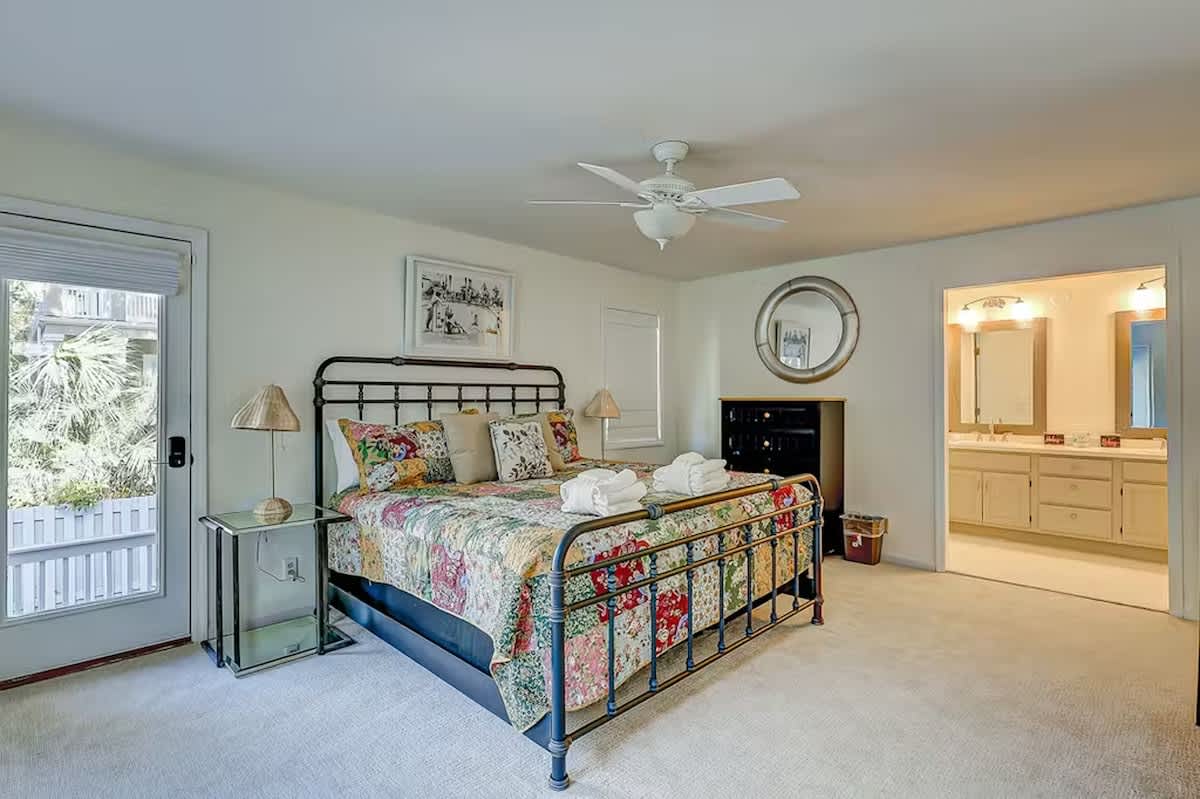 Your spacious master bedroom features a comfortable bed with colorful quilt, ceiling fan, and private bathroom access for ultimate relaxation.