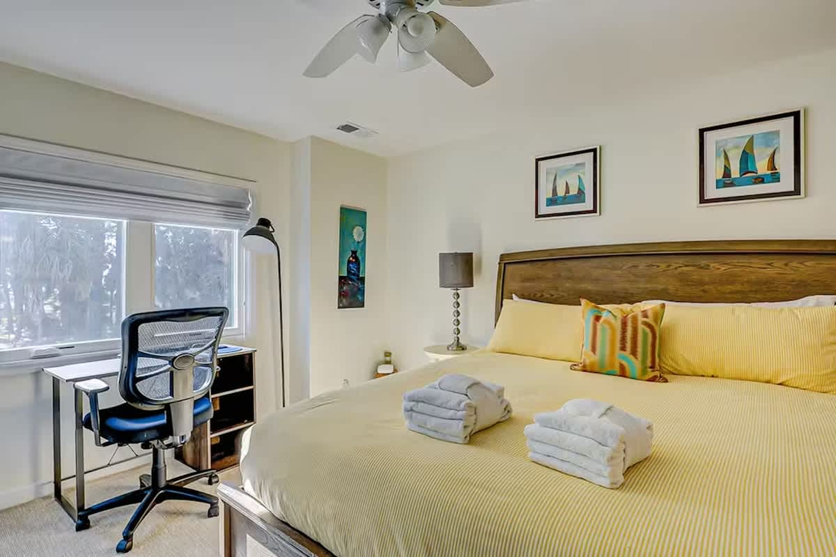 Unwind in your bright bedroom with fresh linens, workspace, and peaceful garden views through large windows.