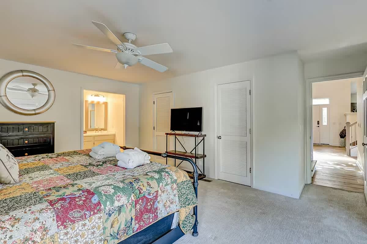Relax in your spacious bedroom featuring a ceiling fan, TV, and patchwork quilt bedding that adds charming character to your restful retreat.
