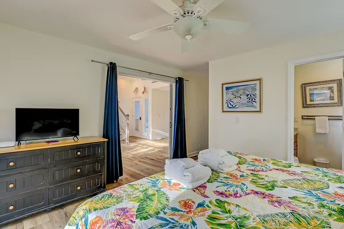 Unwind in your bright bedroom featuring tropical bedding, entertainment center, and fresh towels awaiting your arrival.