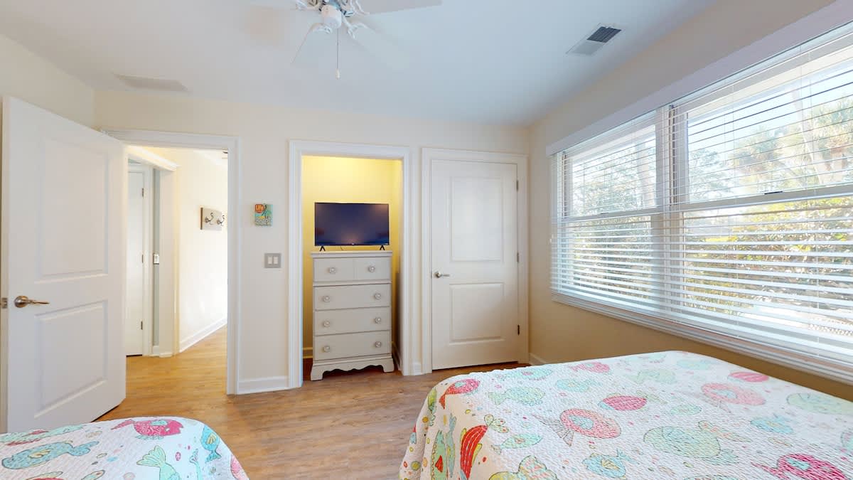 Settle into your bright bedroom with cheerful quilts and garden views through large windows. Modern amenities blend perfectly with cozy comfort.
