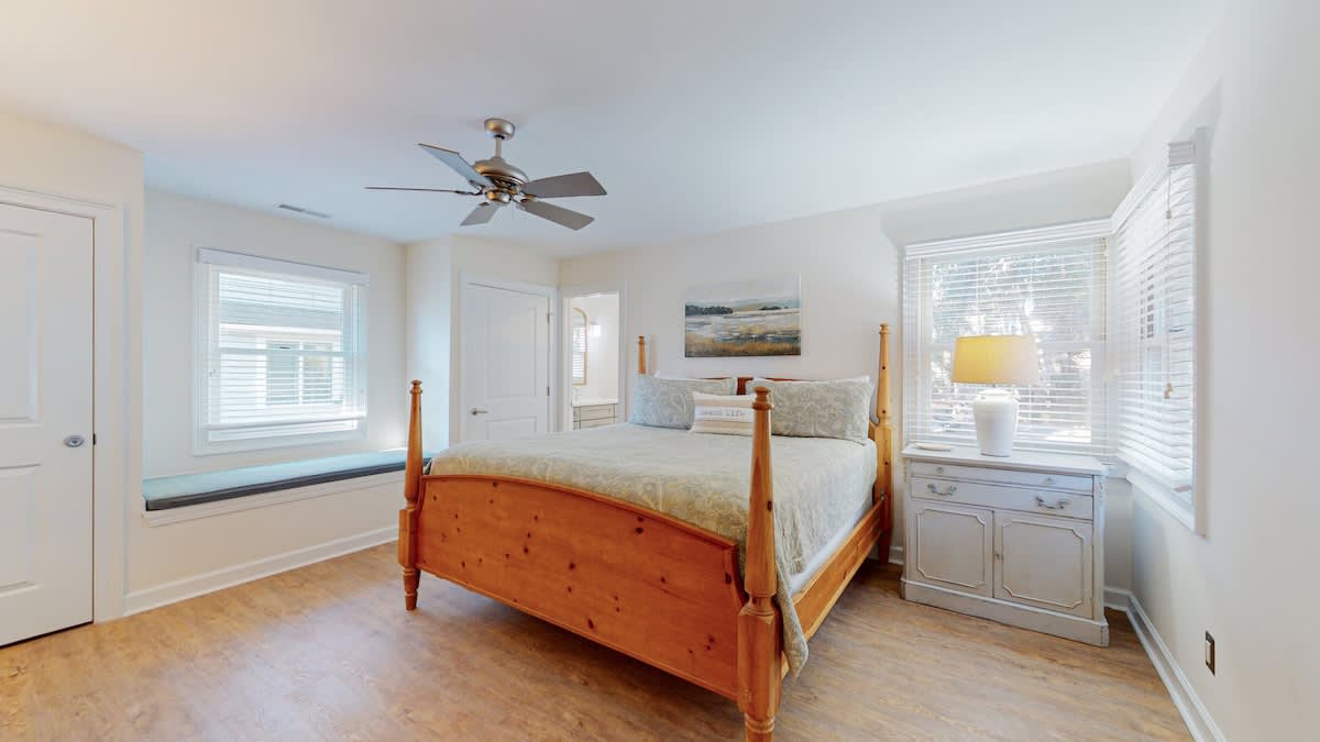 Rest peacefully in your charming bedroom with warm wood furnishings, soft linens, and natural light from multiple windows.