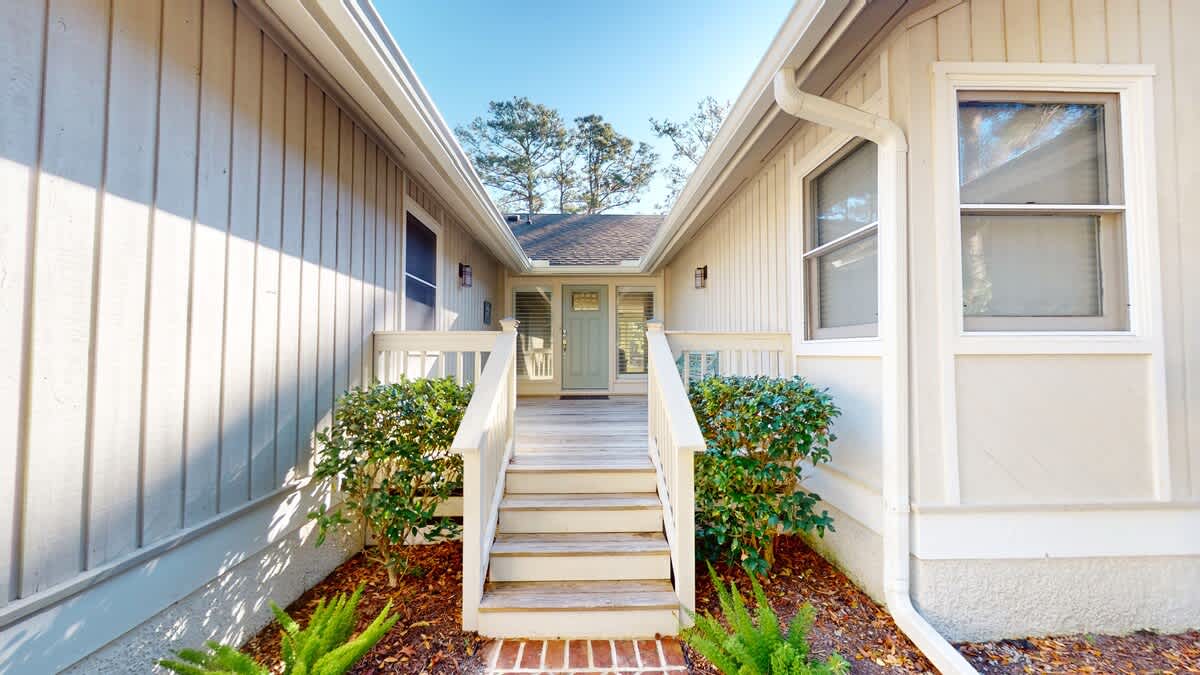 Clean lines and coastal charm welcome guests to this beautifully maintained property entrance with thoughtful landscaping and bright design.