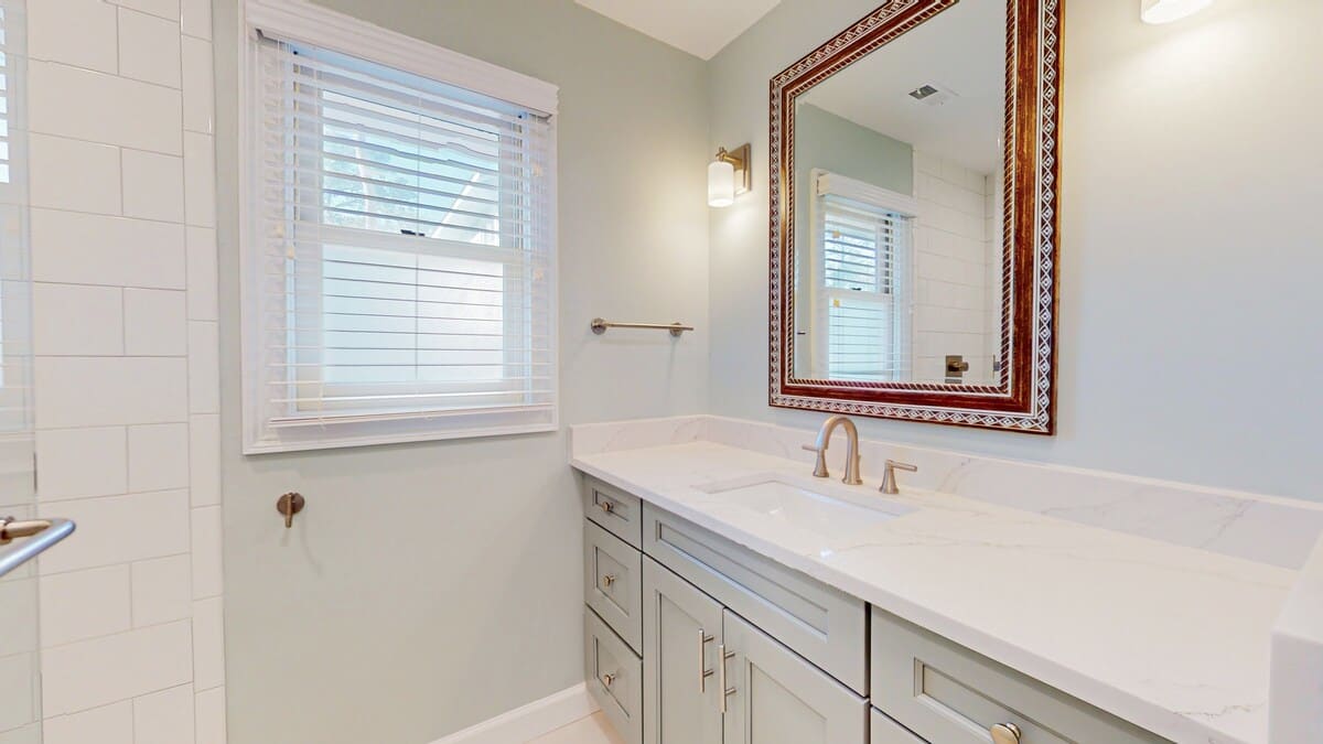 Step into your spa-like bathroom with elegant marble countertops, crisp white cabinetry, and natural light streaming through plantation shutters.