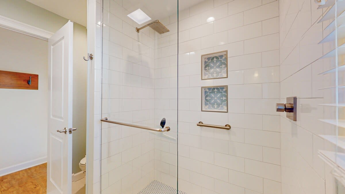 Step into your spacious walk-in shower with elegant tile work, gold fixtures, and thoughtful grab bars for your comfort and safety.