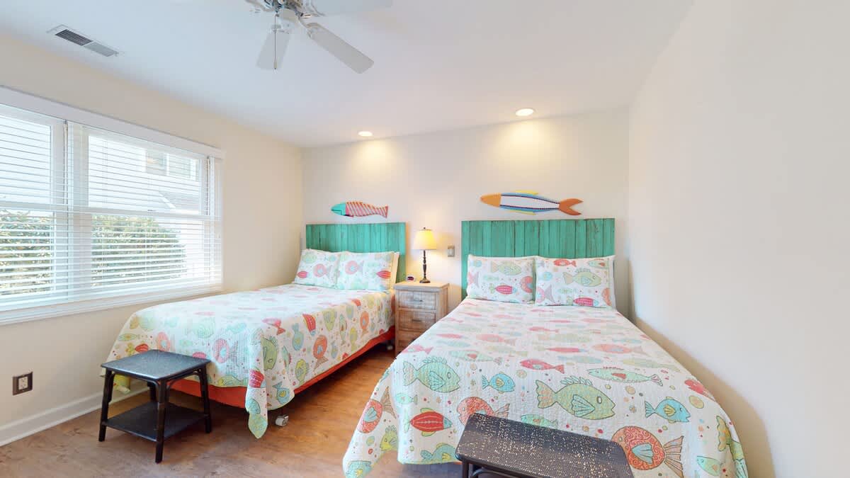 Dive into comfort in your twin bedroom featuring whimsical fish-themed bedding and turquoise headboards that transport you to an underwater paradise.