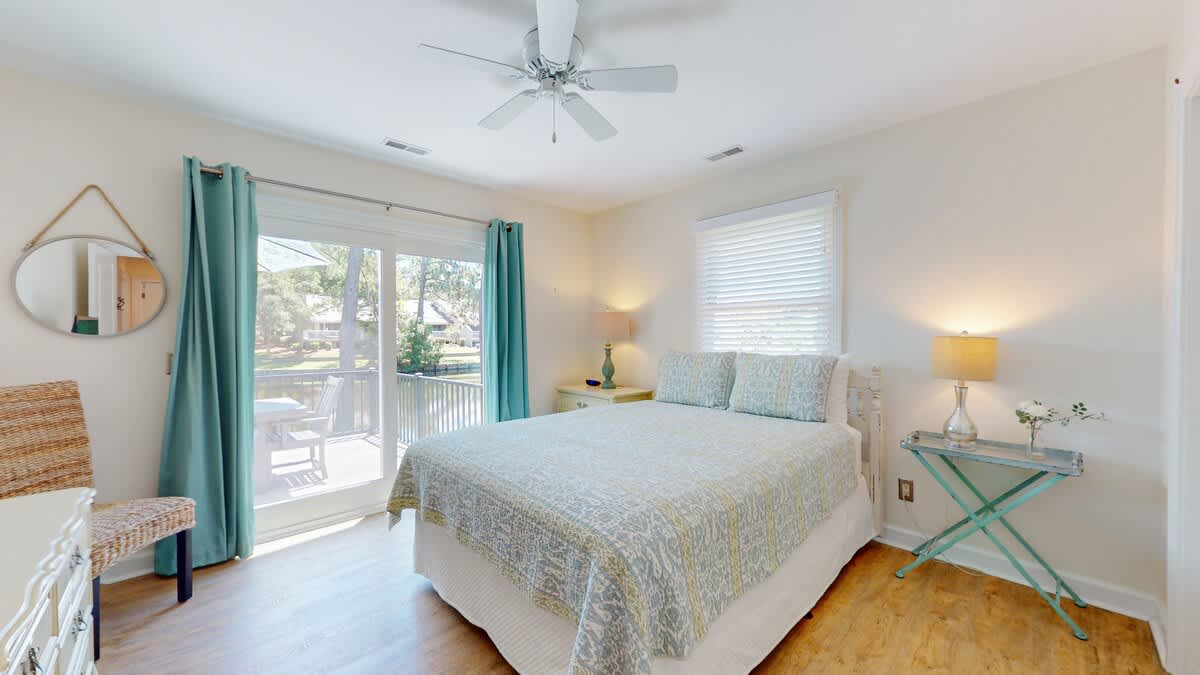 Drift off in your peaceful bedroom with soft coastal colors, cooling ceiling fan, and sunny balcony access for morning coffee.
