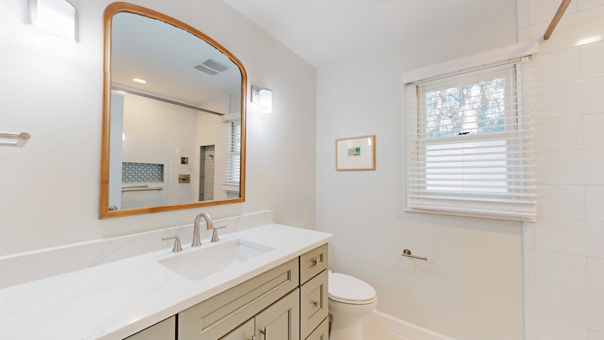 Freshen up in this elegant bathroom with its marble vanity, warm wood accents, and natural light streaming through the window.