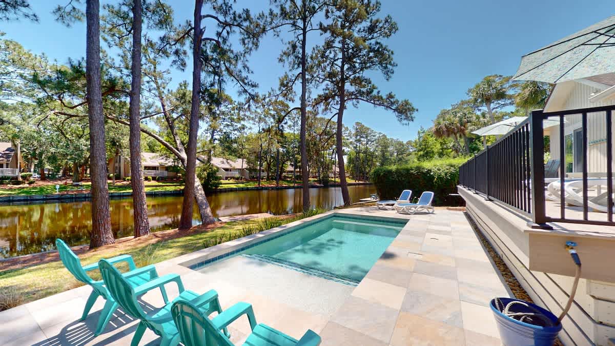 Private pool oasis surrounded by towering pines and peaceful lagoon views for your perfect retreat.