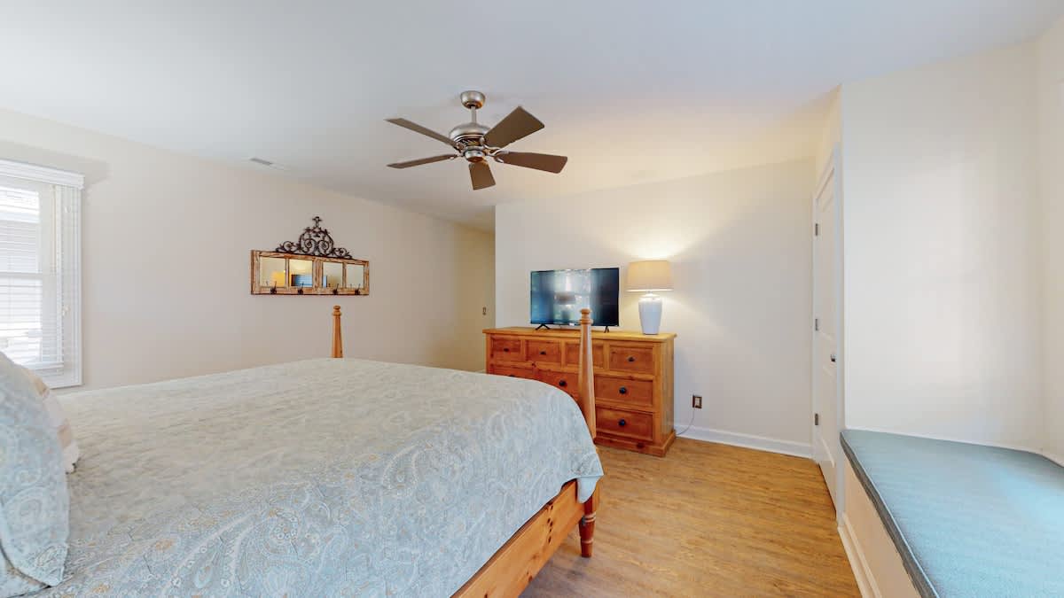 Unwind in your peaceful bedroom with cozy furnishings, ceiling fan, and entertainment center for relaxing evenings.