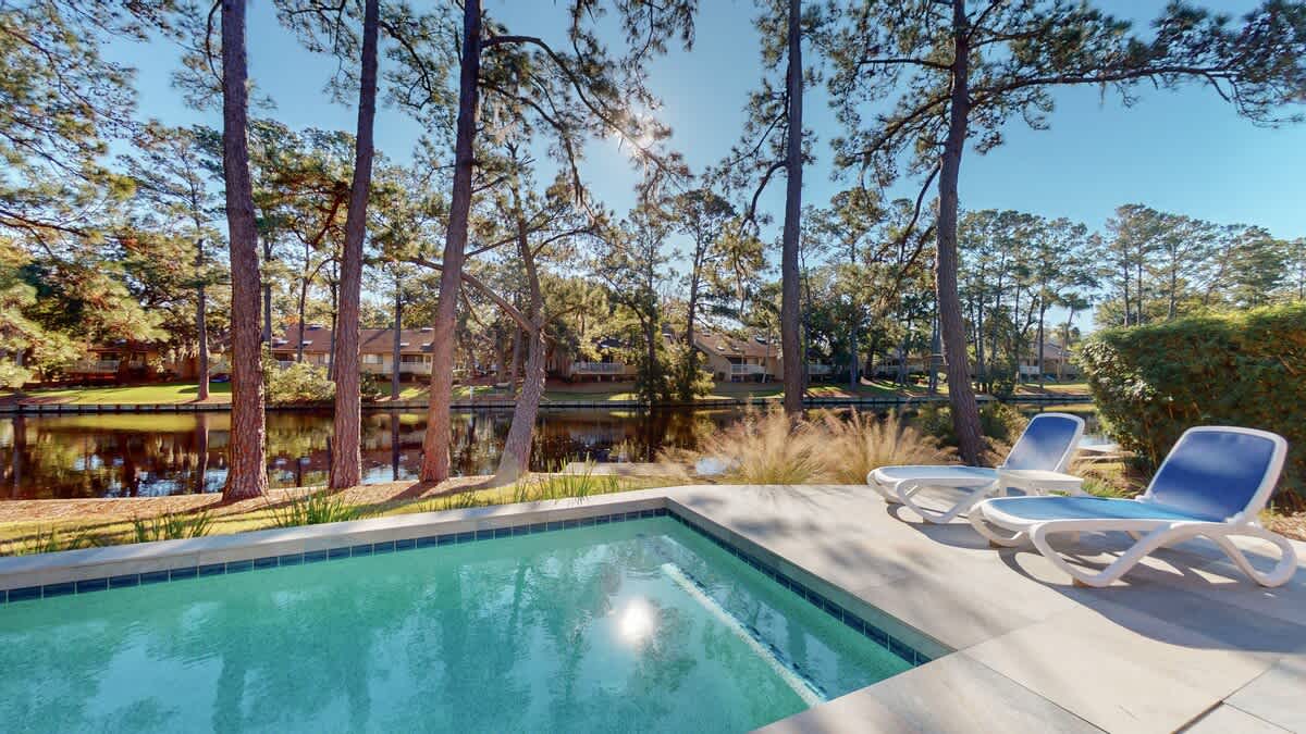 Unwind by your private pool surrounded by towering pines and tranquil water views, where comfortable loungers await your perfect relaxation moment.