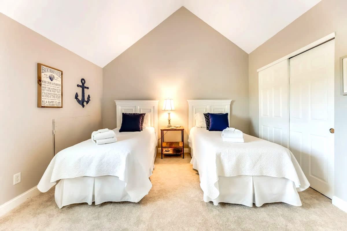 Two crisp twin beds await with nautical charm, plush towels ready for your comfort in this serene coastal retreat.