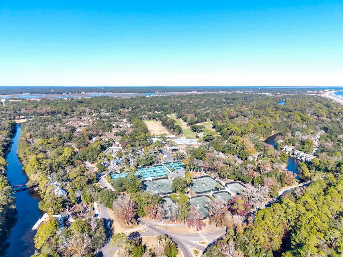 Aerial view of a resort complex nestled among lush trees, with pools and facilities visible near coastal waterways.
