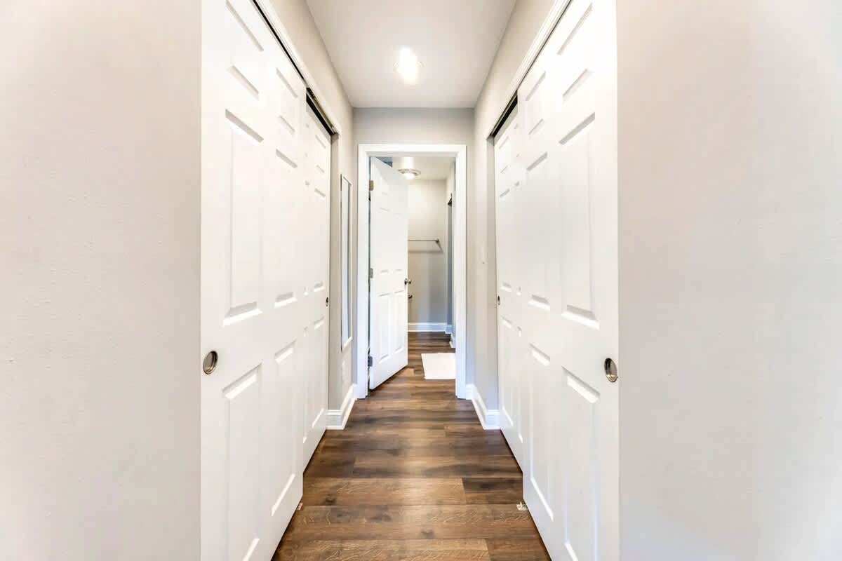Step into your pristine hallway with gleaming hardwood floors and crisp white doors leading to comfortable spaces throughout.