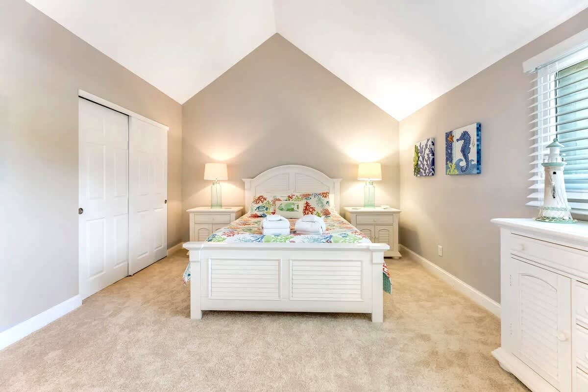 Drift off in this peaceful bedroom with soft carpeting, charming coastal decor, and warm bedside lighting creating your perfect retreat.