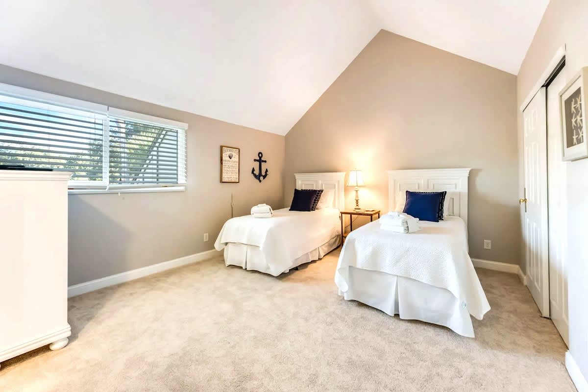 Rest peacefully in your twin bedroom featuring crisp white linens, nautical touches, and natural light streaming through windows.