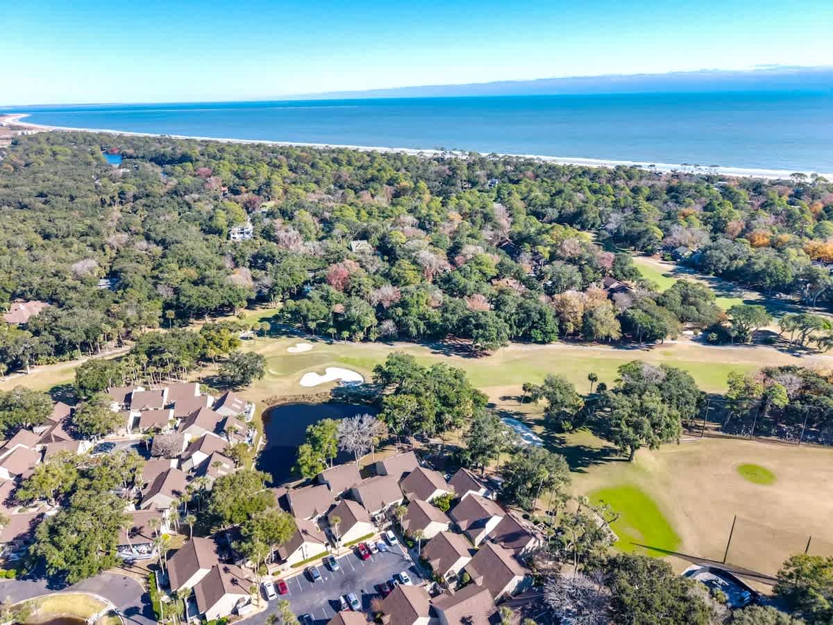 Aerial view showcasing a coastal resort community nestled between pristine beaches and championship golf fairways, surrounded by lush natural landscape.