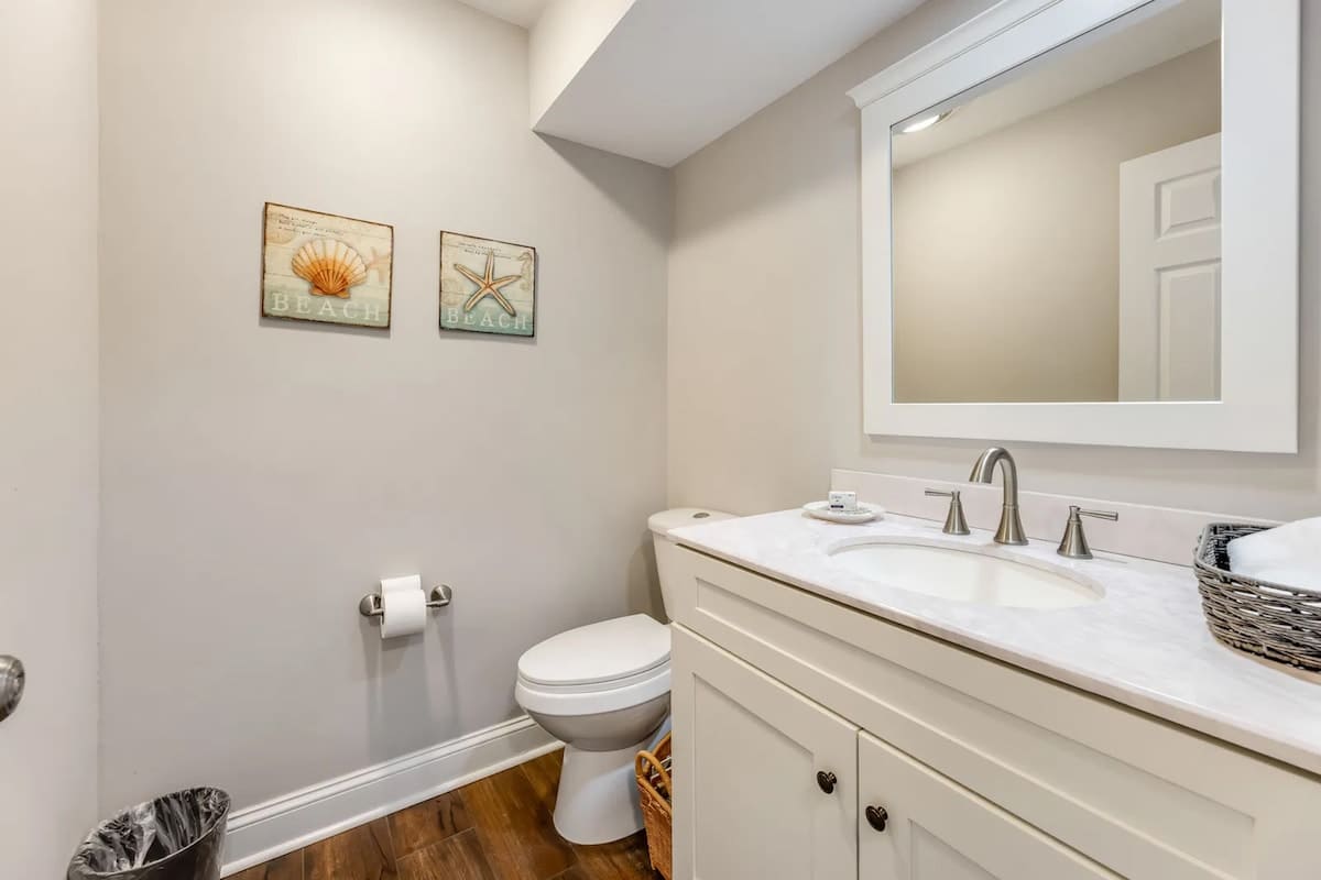 Step into your pristine bathroom featuring coastal charm with seashell artwork, marble countertops, and thoughtful touches that make freshening up a pleasure.