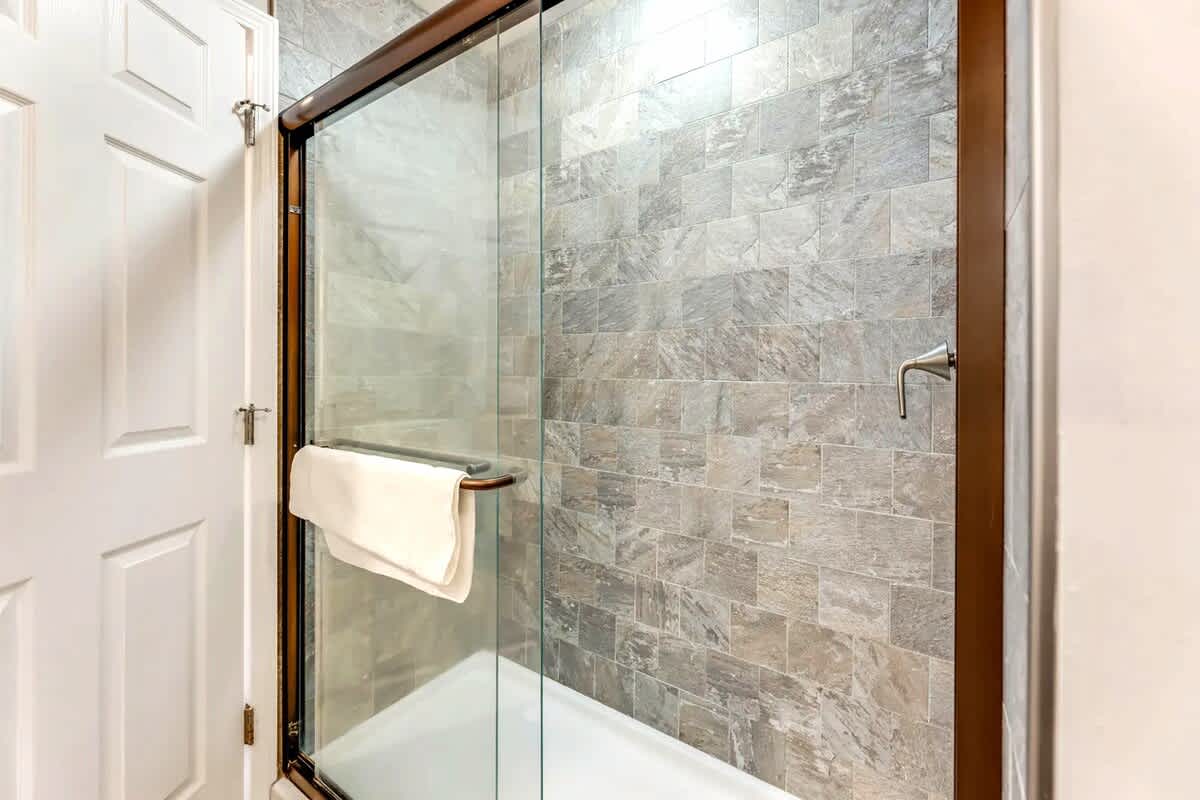 Step into your luxurious glass-enclosed shower featuring elegant natural stone tiles and sleek modern fixtures for a spa-like experience.