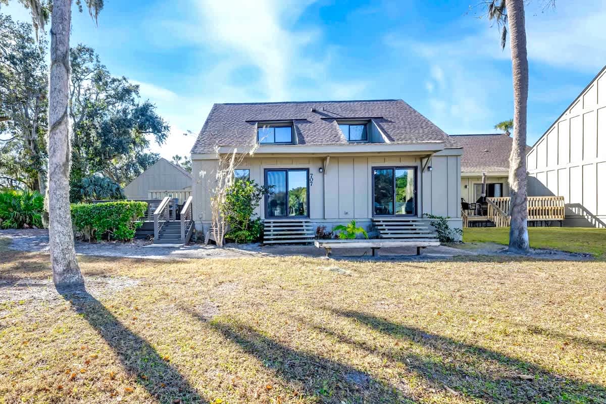 Modern coastal retreat featuring clean lines, spacious lawn, and mature palms creating a serene setting.