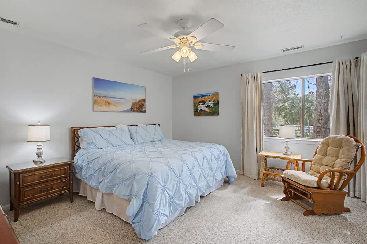 Drift off in this serene bedroom with soft blue linens, coastal artwork, and a cozy reading nook by the window.