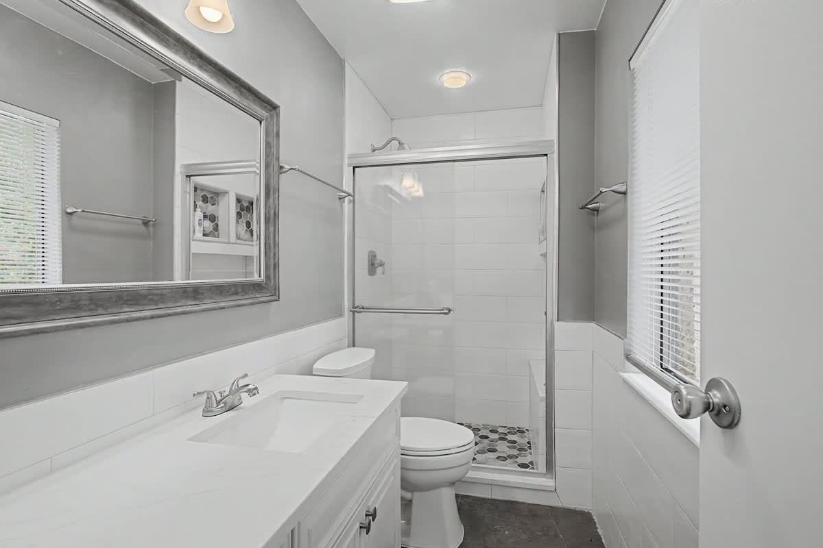 Step into your modern bathroom with pristine white finishes, spacious walk-in shower, and elegant touches throughout.
